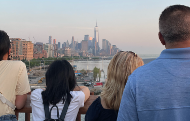 Small private tour group facing away gazing at Manhattan skyline and One World Trade